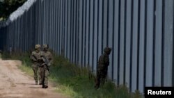 FILE - Polish soldiers patrol along a border fence on the Polish-Belarusian border, in Usnarz Gorny, Poland, Aug. 30, 2023.