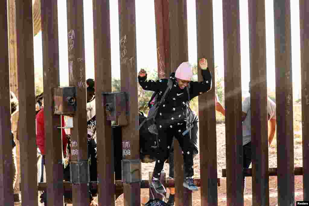 A migrant child jumps to cross the border wall through a gap into the U.S. from Mexico, as the number of migrants surges in the border town of Lukeville, Arizona, Dec. 12, 2023.