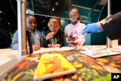 Siswa SD Woodmere, Harvey, La, mengantre untuk mencicipi tonggeret di Audubon Insectarium di New Orleans. (AP/Gerald Herbert)