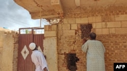 People check a damaged house as smoke billows in southern Khartoum, Sudan, on June 12, 2023.