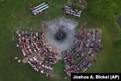 Para peserta dan pemandu duduk di sekitar lingkaran api unggun, Kamis, 20 Juni 2024, di YMCA Camp Kern di Oregonia, Ohio, saat gelombang panas pertama musim panas melanda AS. (Foto: AP/Joshua A. Bickel)
