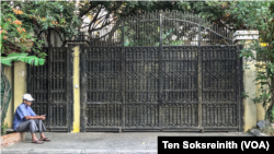 បុរសម្នាក់អង្គុយនៅមុខរបងទ្វានៅគេហដ្ឋានរបស់លោក កឹម សុខា នាថ្ងៃប្រកាសសាលក្រមរបស់លោក នៅរាជធានីភ្នំពេញ ថ្ងៃសុក្រ ទី ៣ ខែមីនា ឆ្នាំ ២០២៣។ (ទែន សុខស្រីនិត/វីអូអេ)