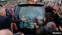 A hearse carrying the coffin of late Irish singer Sinead O'Connor passes by during her funeral procession as fans line the street to say their last goodbye to her, in Bray, Ireland, Aug. 8, 2023. 