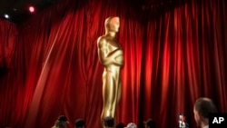 Workers move an Oscar statue during preparations for Sunday's 95th Academy Awards, March 11, 2023, in Los Angeles. 