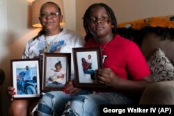 Charlene Roberts and her grandson Princeton Roberts, 11, pose with portraits of her son Kevin and daughter Jessie on Friday, Aug. 4, 2023, in Knoxville, Tenn. (AP Photo/George Walker IV)