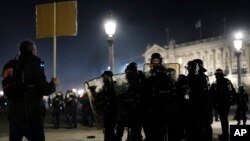A protester faces police officers at Concorde square after a demonstration in Paris, March 16, 2023.