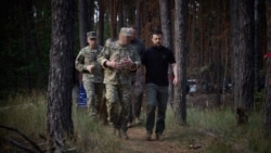 In a photo posted on his X account on July 29, 2024, Ukrainian President Volodymyr Zelenskyy, right, walks with military officials in an area identified as near Vovchansk, in Ukraine's Kharkiv region. The face of the official in the center has been blurred at the source.