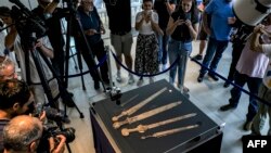 Journalists gather around a showcase displaying a Roman-era javelin and four swords found in a Judean Desert cave, presented at the Jay and Jeanie Schottenstein National Campus for the Archeology of Israel, in Jerusalem, Sept. 6, 2023. 
