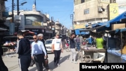 In this photo of Palestine Street in Hasaka, Syria, the government-controlled stores sit on the right and Kurdish-controlled stores sit on the left, March 22, 2024.