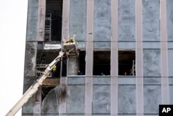 Workers clean a part of a damaged skyscraper in the 'Moscow City' business district after a reported drone attack in Moscow, Aug. 23, 2023.