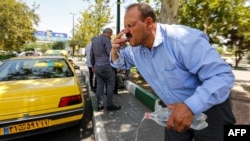 FILE - A man rinses his face with water from a bottle to cool off during a heat wave in Tehran on July 11, 2023. As the heat wave continues, the Iranian government declared a two-day holiday as a public health measure.
