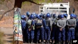 Police officers armed with batons, teargas, and guns stand outside the elections results center in Harare, Zimbabwe, Aug. 25, 2023.