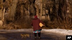 A woman carries a box of humanitarian aid in the village of Blahodativka, Ukraine, Feb. 22, 2023. 
