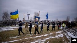 The coffin of Oleksandr Maksymenko, 38, is carried by Ukrainian officers during his funeral in his home-village Kniazhychi, east of Kyiv, Feb. 13, 2023. Oleksandr, a civilian who was a volunteer in the armed forces of Ukraine, was killed in the fighting in the Bakhmut area.