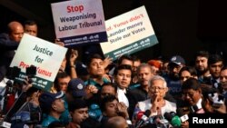 Bangladeshi Nobel peace laureate Muhammad Yunus (in white vest) gestures in front of a court house after being sentenced to six months in prison in a labor law violation case, in Dhaka, Bangladesh, Jan. 1, 2024.