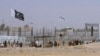 FILE - Pakistani and Taliban flags flutter on their respective sides while people walk through a security barrier to cross the Pakistan-Afghan border in Chaman, Pakistan, Aug. 18, 2021.
