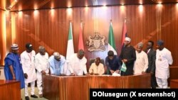 Shugaba Bola Tinubu a zagaye da wasu jami'an gwamnatinsa yayin da ya rattaba hanu akan dokar rancen dalibai.