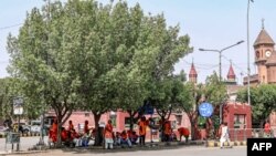 Porters sit under the shade of a tree as they wait for passengers on a hot summer day outside the Lahore railway station in Lahore, Pakistan, May 22, 2024.