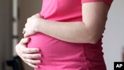 FILE - A pregnant woman stands for a portrait in Dallas, May 18, 2023. 