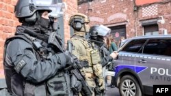 Anggota unit khusus kepolisian Prancis, berjaga saat Menteri Dalam Negeri dan Luar Negeri Prancis Gerald Darmanin berbicara dengan petugas setelah berlangsungnya "operasi pembersihan XXL" terhadap geng narkoba Prancis di Roubaix, 25 Maret 2024. (Denis CHARLET / AFP)