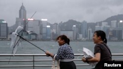 A woman holds a broken umbrella as Super Typhoon Saola approaches, in Hong Kong, China, Sept.1, 2023. 