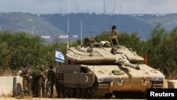 Israeli soldiers stand near to a tank near Israel's border with Lebanon in northern Israel, Oct. 16, 2023