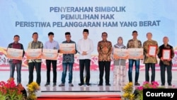 Presiden Jokowi berfoto bersama para penerima sertifikat program pelaksanaan rekomendasi penyelesaian non-yudisial pelanggaran hak asasi manusia (HAM) berat masa lalu di Indonesia, di Rumah Geudong Kecamatan Glumpang Tiga Kabupaten Pidie, Aceh, Selasa (27/6). (Setpres RI)
