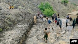Residents shovel mud following flash floods after heavy rainfall at Pesgaran village in Afghanistan's Panjshir province on July 15, 2024. At least 35 people were killed and 230 injured after heavy rain in eastern Afghanistan, a local official said.