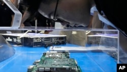 Posjetilac gleda čip prikazan na štandu kineske kompanije Kunlun Core na Svjetskoj konferenciji o umjetnoj inteligenciji u Šangaju. (24. jula 2023.)