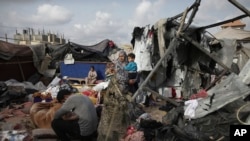 FILE - Displaced Palestinians inspect their tents destroyed by Israel's bombardment, adjunct to an UNRWA facility west of Rafah city, Gaza Strip, May 28, 2024.