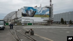 A woman pats a dog near the nuclear power plant in Chernobyl, Ukraine, April 26, 2023.
