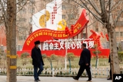 资料照：新疆和田居民走过街头竖立的社会主义核心价值观的宣传牌。（2021年3月22日）