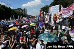 Para demonstran dalam pawai peringatan 37 tahun revolusi "People Power" yang menggulingkan ayah Presiden Marcos Jr, di Quezon City, Filipina, Sabtu, 25 Februari 2023. (Foto: Jam Sta Rosa/AFP)