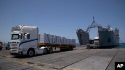 FILE - Trucks arrive loaded with humanitarian aid at the U.S.-built floating pier before reaching the beach on the Gaza coast, June 25, 2024. U.S. defense officials said on July 12, 2024, that there is no date set for re-attaching the pier, which is currently dismantled.