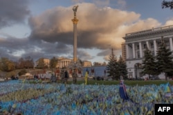 Pedestrians wearing military uniforms walk past flags bearing symbols and colors of Ukraine that commemorate the country's fallen soldiers at Independence Square in Kyiv, on Oct. 23, 2023, amid the Russian invasion of Ukraine.