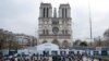 People stand in front of Notre-Dame de Paris Cathedral during the reconstruction work on the Ile de la Cite in Paris, on Dec. 8, 2023, one year to the day before the cathedral, which was ravaged by fire in 2019, is due to reopen. 