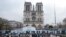 People stand in front of Notre-Dame de Paris Cathedral during the reconstruction work on the Ile de la Cite in Paris, on Dec. 8, 2023, one year to the day before the cathedral, which was ravaged by fire in 2019, is due to reopen. 