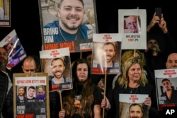 Families and supporters of Israeli hostages held by Hamas in Gaza hold their photos and shout slogans during a rally calling for their release, in Tel Aviv, Dec. 30, 2023.