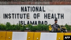A delivery boy rides past the building of National Institute of Health (NIH), a Pakistani research institute mainly responsible for biomedical and health related research, in Islamabad, Aug. 16, 2024. 