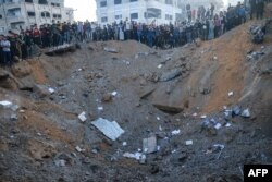 Warga Palestina berdiri di tepi lubang sebagai akibat serangan Israel di Rafah di Jalur Gaza selatan pada 3 Desember 2023. (Foto: AFP)