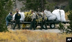 FILE - Mono County deputies watch as a member of a private salvage company ties down some of the bagged wreckage recovered from the crash site of adventurer Steve Fossett, near Mammoth Lakes, California, Oct. 3, 2008. The billionaire entrepreneur disappeared in September 2007 while on a solo flight from a Nevada ranch.