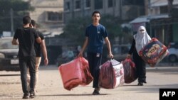 ជន​ប៉ាឡេស្ទីន​កាន់​របស់​របរ​នៅ​ពេល​ពួកគេ​ដើរ​នៅ​តំបន់​ហ្គាហ្សា​ភាគ​ខាង​ត្បូង​ថ្ងៃ​ទី៨ ខែ​វិច្ឆិកា ឆ្នាំ២០២៣។