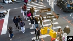 Shoppers holding bags cross Broadway on Black Friday in New York, Nov. 24, 2023.
