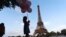 ILUSTRASI - Seorang turis memegang seikat balon, saat berjalan bersama keluarganya di tepian sungai Seine depan menara Eiffel Tower, Paris, 29 Juli 2024.