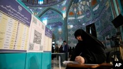 Seorang perempuan mengenakan hijab sedang mengisi surat suara di tempat pemungutan suara di Tehran, Iran, 1 Maret 2024. (Foto: Vahid Salemi/AP Photo)
