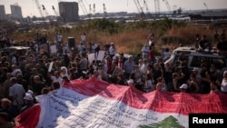 People hold a giant Lebanese flag during a march, as Lebanon marks the fourth anniversary of the explosion in the port of Beirut, Aug. 4, 2024. 