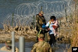 FILE - Migrants are taken into custody by officials at the U.S.-Mexico border, in Eagle Pass, Texas, Jan. 3, 2024.