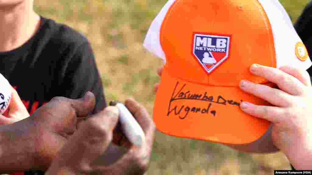 Dennis Kasumba signe une casquette pour un enfant lors de son deuxième match avec l'équipe de baseball des Frederick Keys au Harry Grove Stadium de Frederick, Maryland, le 3 juin 2023. (VOA/Arzouma Kompaore)