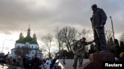Ukrainian soldier Andriy Gomelyak pays his respect to Oleksandr Matsievskyi, who served with him in one unit and was executed by Russian troops in 2022, during the opening ceremony of Matsievskyi's statue in Nizhyn, Ukraine, Nov. 25, 2023. 