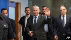Israeli Prime Minister Benjamin Netanyahu, center, waves to the media as he arrives at a cabinet meeting in Jerusalem, July 17, 2023. Netanyahu pledged to crack down on no-shows for military reserve duty.